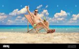 cheerful-young-man-sitting-at-the-beach-and-holding-a-beer-bottle-2RGA2RG.jpg